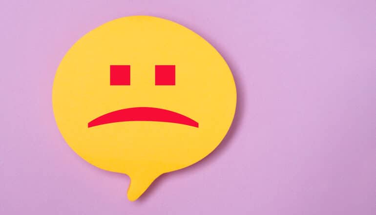 A yellow speech bubble contains a frowning face.