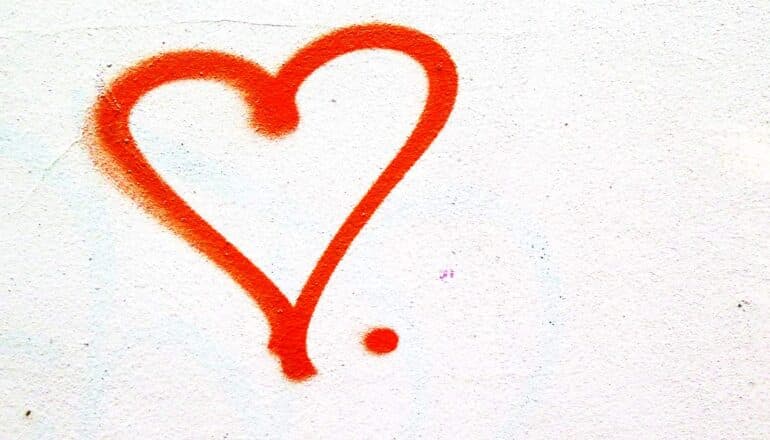 A heart spray painted in red on a white wall.