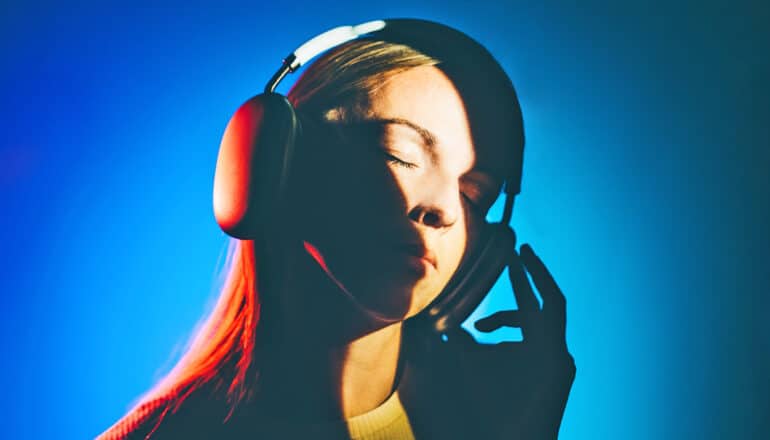 A woman listens to music while wearing large over-the-ear headphones.